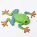 Green toy frog with blue and orange gradient legs in a high-quality top view studio shot - Blue Limbs