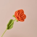Handmade crochet orange rose flower with green leaves on light pink background - Orange Rose