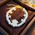 Vista macro detallada de la pulsera de perlas de doble capa con colgante de camelia blanca - Juego de 2 Pulseras de Perlas de Camelia
