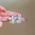 Close-up of elegant light blue flower earrings with crystal clusters held by hand - Blue