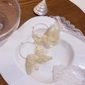 Dettaglio di orecchini a cerchio con fiori in tessuto crema su un piatto di porcellana bianca - Bianco Sporco