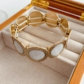 Dettaglio del bracciale retrò dorato con inserti bianchi in una scatola regalo di legno - Rivestimento Ovale Bianco / Oro-Bianco