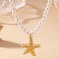 Elegante collar de perlas con colgante de estrella de mar dorada sobre fondo beige suave - Dorado
