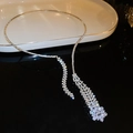 Detail einer silbernen Y-Quastenkette mit funkelnden Zirkonia auf einem Luxustablett - Silber