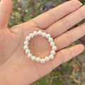 White faux pearl elastic beaded ring for girls displayed on a hand palm with nature background - 6MM Cream White Pearl Decorative Chain
