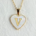 Detailed macro shot of a gold heart necklace pendant with shell inlay and letter V - Letter V / Gold