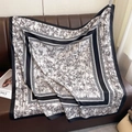 Classic black and white bamboo ink print silk square scarf elegantly draped on leather - Black
