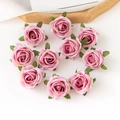 Nahaufnahme von zehn rosa künstlichen Seidenrosenköpfen mit Blättern auf weißem Grund - Rosé