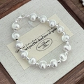 Detailed top view of silver bead bracelet with lobster clasp on a wooden jewelry tray - 925 Silver / 8mm Style