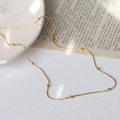 Minimalist gold beaded snake chain necklace displayed on a textured white surface - Gold (J716 Bead Chain Anklet)
