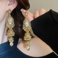 Close-up of golden hollow Jhumka earrings with clear gemstones and drop pendants - 2# Steel Pin-Gold