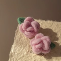 Close-up of pink flocked rose earrings with green leaves on a textured paper background - Pink