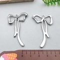 Ciondoli a fiocco in argento per gioielli fai-da-te mostrati con un righello - Fiocco Lungo - Argento