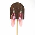 Close-up of pink boho feather earrings with bead details on a wooden display stand - Dusty Pink