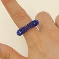 Detailansicht eines blauen Spiral-Massagerings am Finger zur gezielten Stressbewältigung - Blau