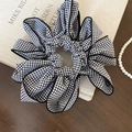 Dettaglio macro dello scrunchie a fiori vichy bianco e nero su un libro d'epoca - Scrunchie-Nero/Stile Gingham Nero Bianco / Nero