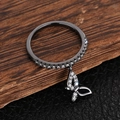 Detail of black metal ring featuring a sparkling zircon butterfly pendant and paved stones - US 7 / Black & Gold