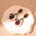 Close-up of vintage flower drop earring with purple enamel and green crystal accents - Purple Flower Drop Earrings