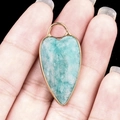 Amazonite heart pendant with golden metal edge and natural texture shown in hand - Amazonite