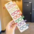 Set of seven heart-shaped matte macaron hair clips on white card held by hand - Double Heart 7-Color Set