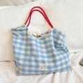 Detail of blue and white checkered tote bag with red braided handles and brand label - Plaid Blue