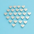 Vista macro de 26 cuentas de corazón plateadas con grabados del alfabeto A-Z en fondo azul - Letra R / Solo Cuenta Color Acero