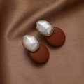 Detail of vintage gold-rimmed pearl earrings resting on elegant brown silk fabric - Brown Geometric Style