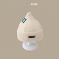 Detail of cream knitted baby hat with soft ribbed texture and decorative woven labels - U0 Single Cap Beige (2 Months - 2 Years)