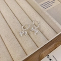 Macro shot of silver bow pendant earrings with beaded hoop detail on beige jewelry box - Silver Bow Knot Ear Buckle