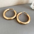 Detailed view of polished thick gold hoop earrings on a textured grey background - Gold Smooth Polished (5cm)