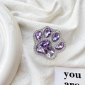 Detailopname van luxe kattenpoottelefoongreep met paarse kristallen op wit textiel - Paars