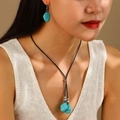 Primo piano di una modella con set di collana e orecchini in turchese in stile etnico - Forma Irregolare (11082)