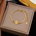 Détail d'un bracelet en acier doré avec trèfle sur un fond en soie élégant et luxueux - Bracelet trèfle en acier inoxydable doré (SLE2083)