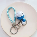 Blue and white woven rope keychain with matching bells on a ceramic plate - Blue White