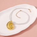 Macro detail of a gold conch shell pendant on a white woven rope with adjustable chain - Necklace G-Conch Braided Cord