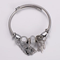 Macro detail of silver charm bracelet with feather pendants and heart lock - Bohemian Heart & Feathers Style