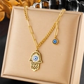 Goldene Hamsa-Hand-Halskette mit blauem bösem Blick-Anhänger auf Schmuckkissen - Strass Hamsa Hand Böser Blick Stil (N2619)