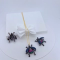 Detailed view of beetle pendant and earrings set with vibrant blue and pink gemstones - Colorful Gemstone Dark Beetle Pendant