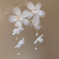 Dettaglio ravvicinato di orecchini a fiore in chiffon bianco con catenine e perle - Bianco