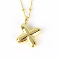 Macro shot of polished gold-finished X-shaped pendant necklace with reflective metal surface - Letter X