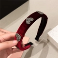 Elegant red velvet headband with heart rhinestones shown in a hand-held close-up view - Burgundy