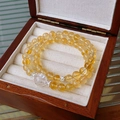 Gros plan d'un bracelet en cristal blanc avec perle sculptée dans un écrin en bois - 20# Jaune