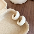 Close-up of white matte C-shaped resin earrings placed in a beige textured tray - White Matte C-Shape