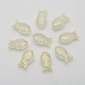 Macro shot of 9 rainbow plated fish-shaped crystal beads arranged in a circle on white background - Crystal Yellow