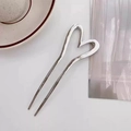 Dettaglio della forcina a U in argento con design a cuore cavo su tessuto bianco - Argento lucido