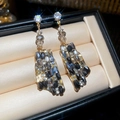 Dettaglio di orecchini pendenti geometrici con cristalli neri su vassoio in velluto - Oro-Nero