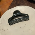 Detailed close-up of dark green resin hair claw on a ceramic plate highlighting glossy finish - Dark Green