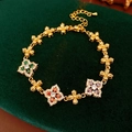 Nahaufnahme eines goldenen Vintage-Armbands mit bunten Zirkonblumen auf Samt - Gold-Mehrfarbig