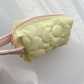 Detailed close-up of yellow quilted polyester cosmetic bag with floral stitching patterns - Yellow
