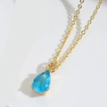 Macro shot of sky blue teardrop crystal pendant on thin gold chain necklace - Transparent Blue